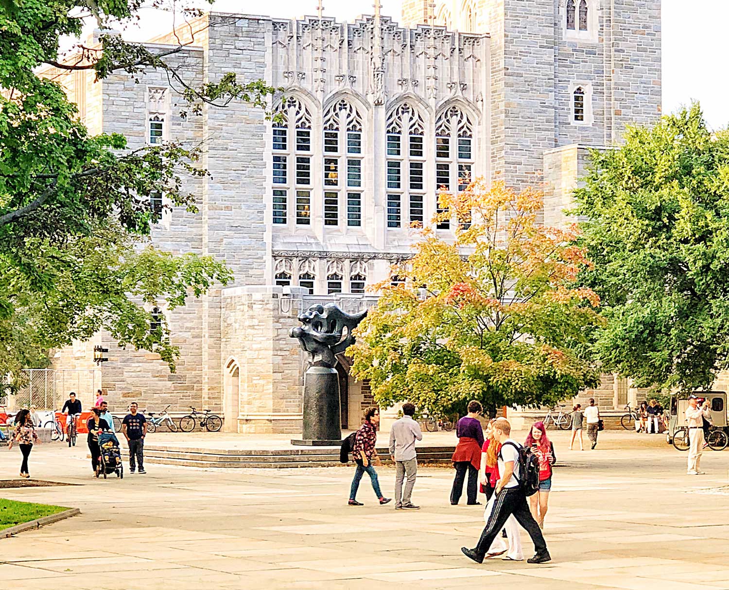 A group of people walking on the sidewalk near a building.